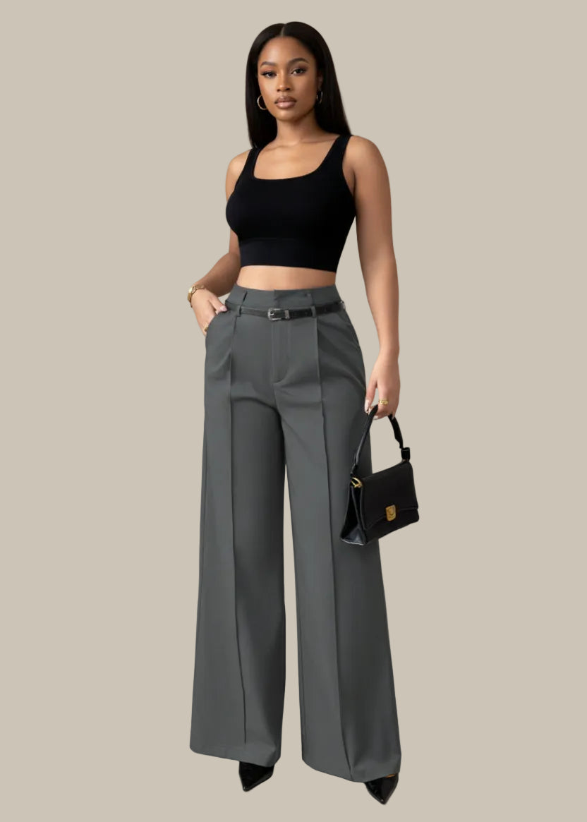 Person wearing gray wide-leg pants holding a black handbag against a neutral background