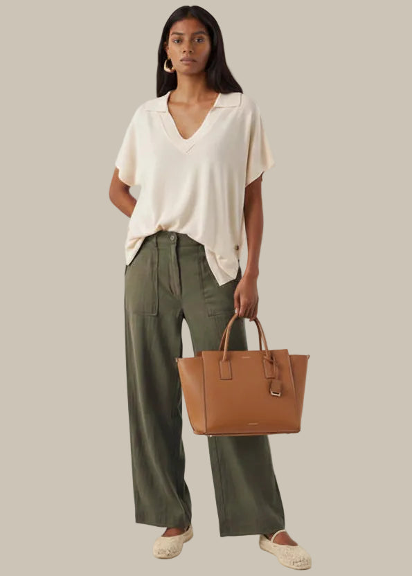 Woman wearing a beige top and green pants on a white background