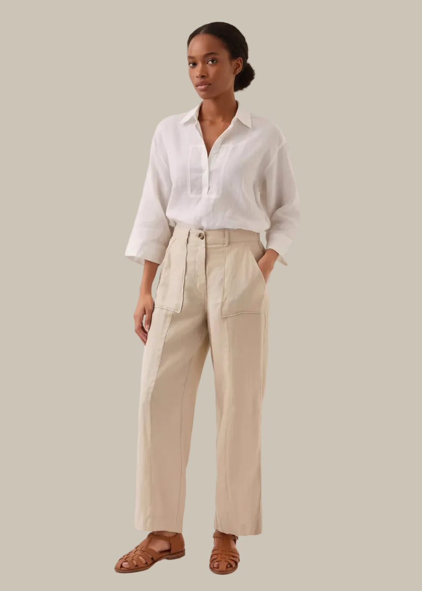 Person wearing beige pants and a white shirt on a plain background