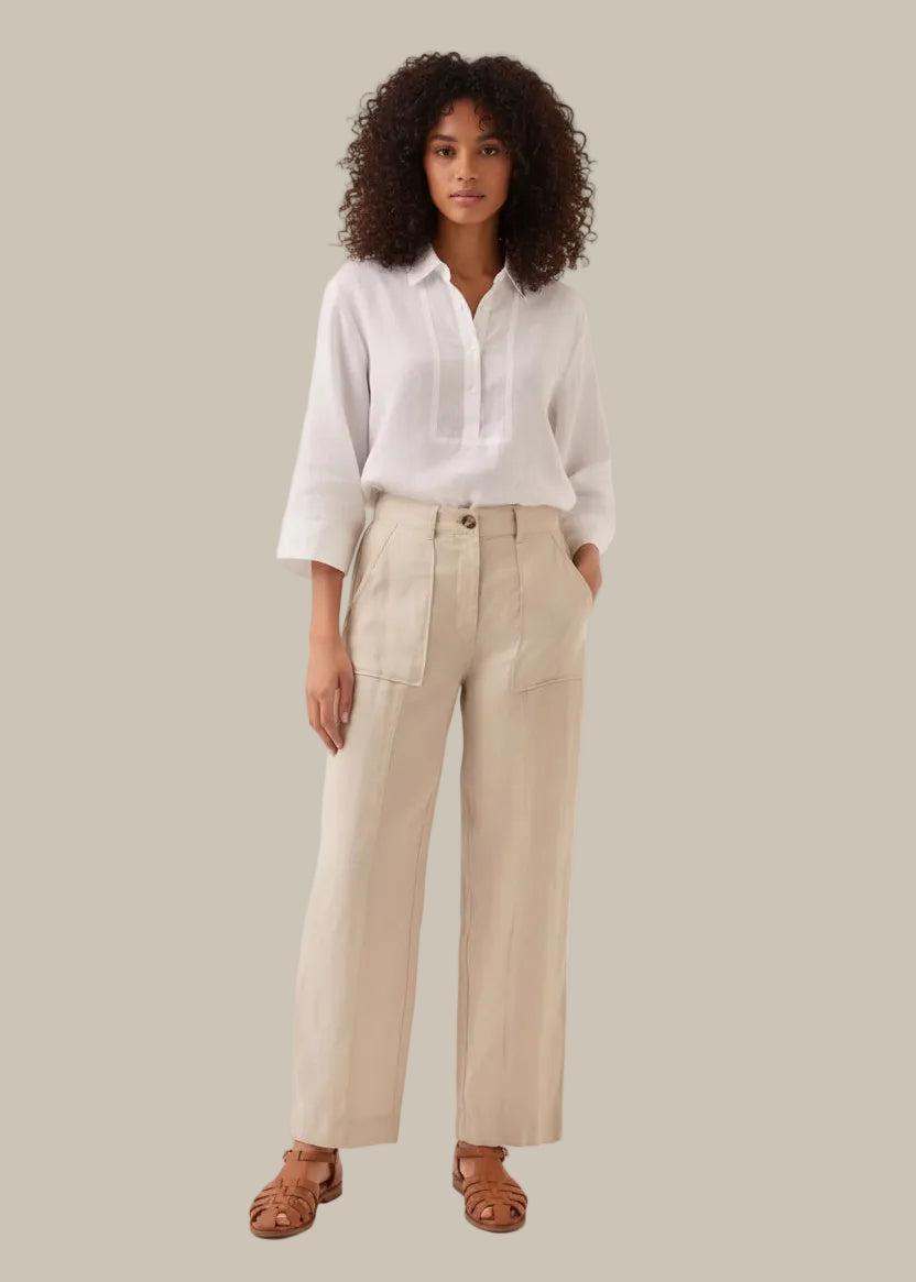 Person wearing beige pants and a white shirt on a plain background