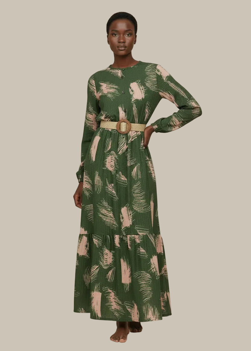 Woman wearing a green patterned dress with a belt on a beige background