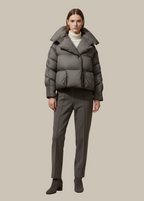 Person wearing a gray puffer jacket and pants on a beige background