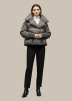 Woman wearing a gray puffer jacket and black pants on a beige background