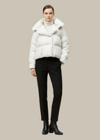 Person wearing a white puffer jacket and black pants on a beige background