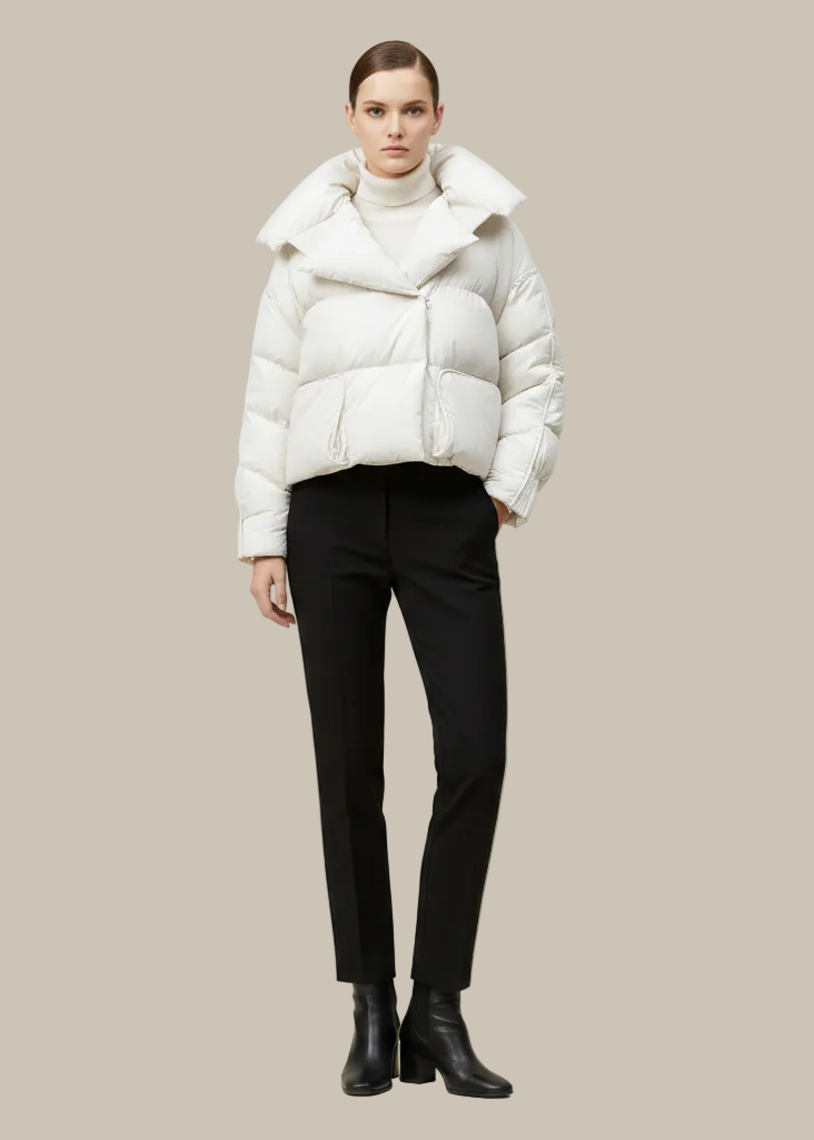 Person wearing a white puffer jacket and black pants on a beige background