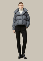 Person wearing a gray puffer jacket, black pants, and black boots on a beige background