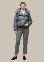 Person wearing a gray puffer jacket and pants on a beige background