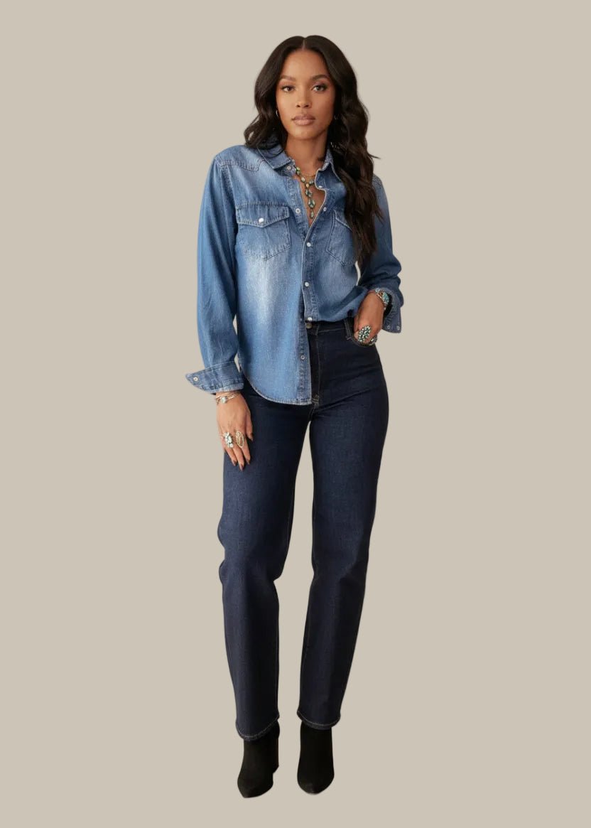 Woman wearing a blue denim shirt and dark jeans on a white background