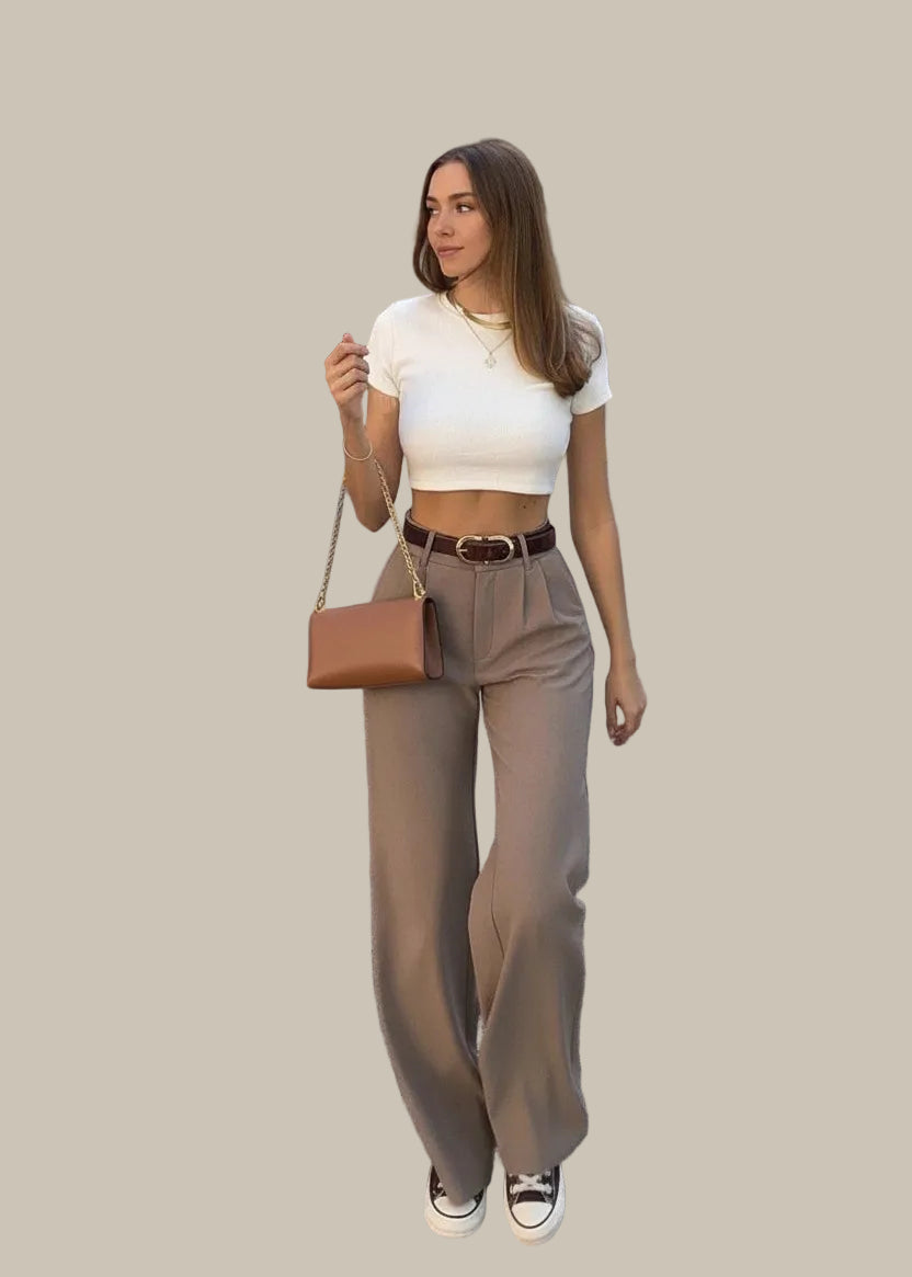 Woman in white crop top and beige pants walking on a street.