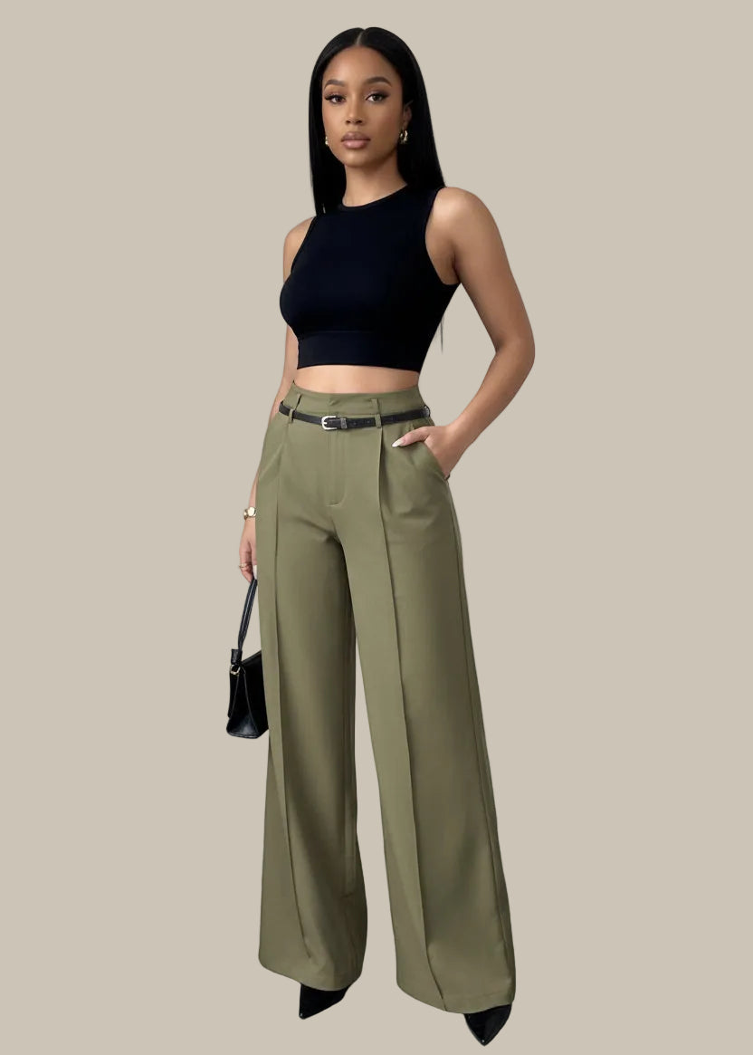 Person wearing olive green wide-leg pants with a black top and handbag against a neutral background