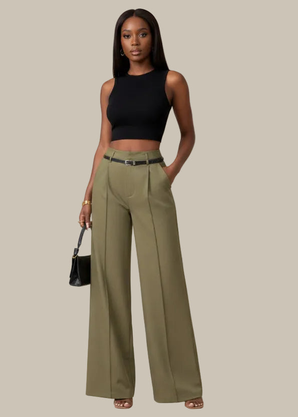 Person wearing olive green wide-leg pants with a black top and handbag against a neutral background